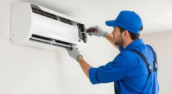 Technician servicing an open wall-mounted air conditioning unit
