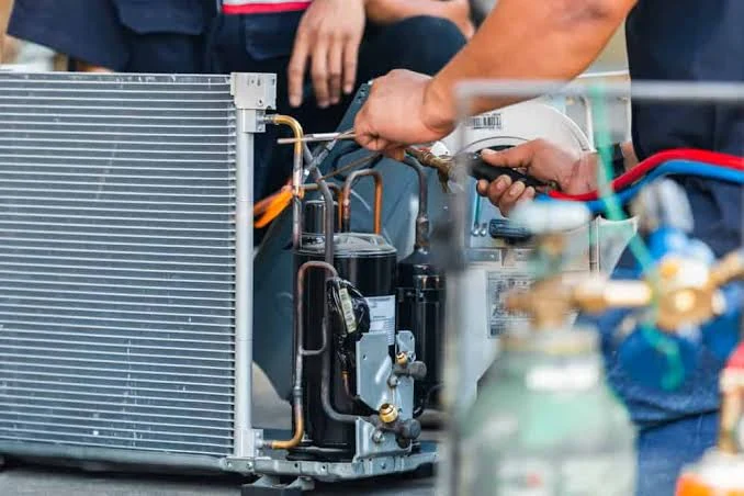 Close-up of an air conditioning compressor and refrigerant piping being repaired