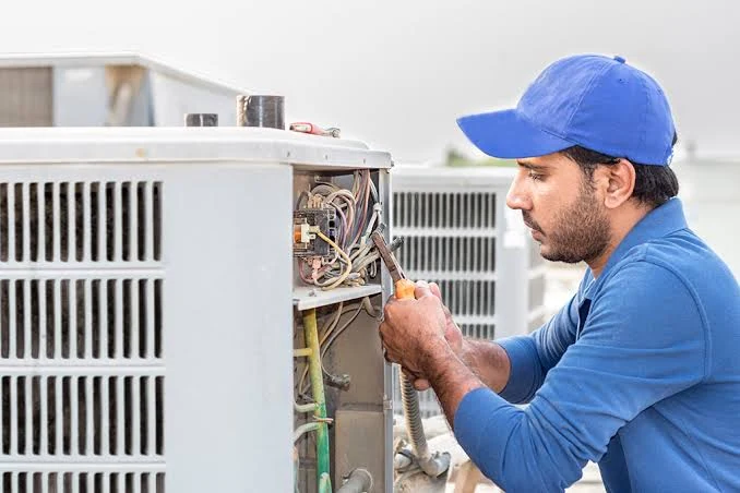 Technician checking the wiring of an outdoor air conditioning condenser